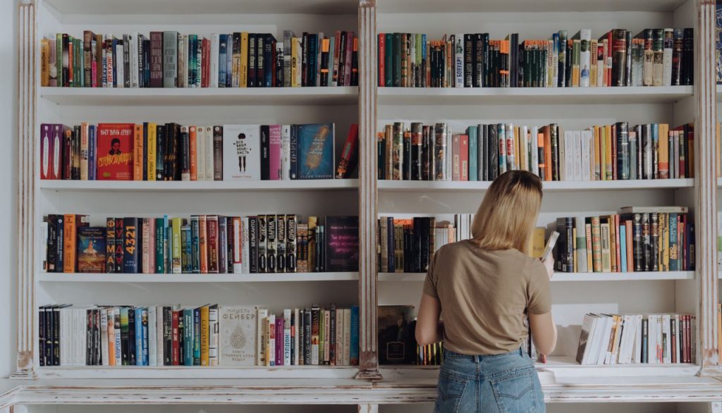 mulher-pegando-livro-biblioteca